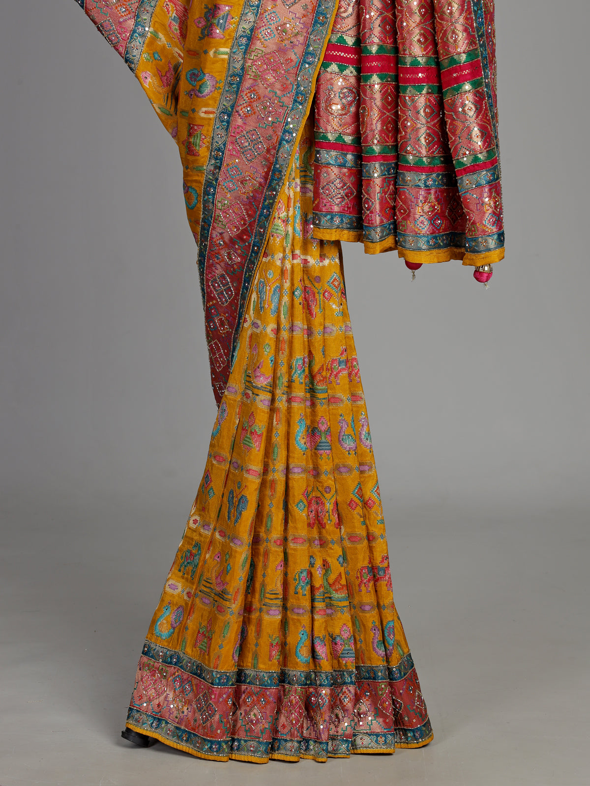 Mustard yellow modal satin saree with colourful motifs and tassel detailing