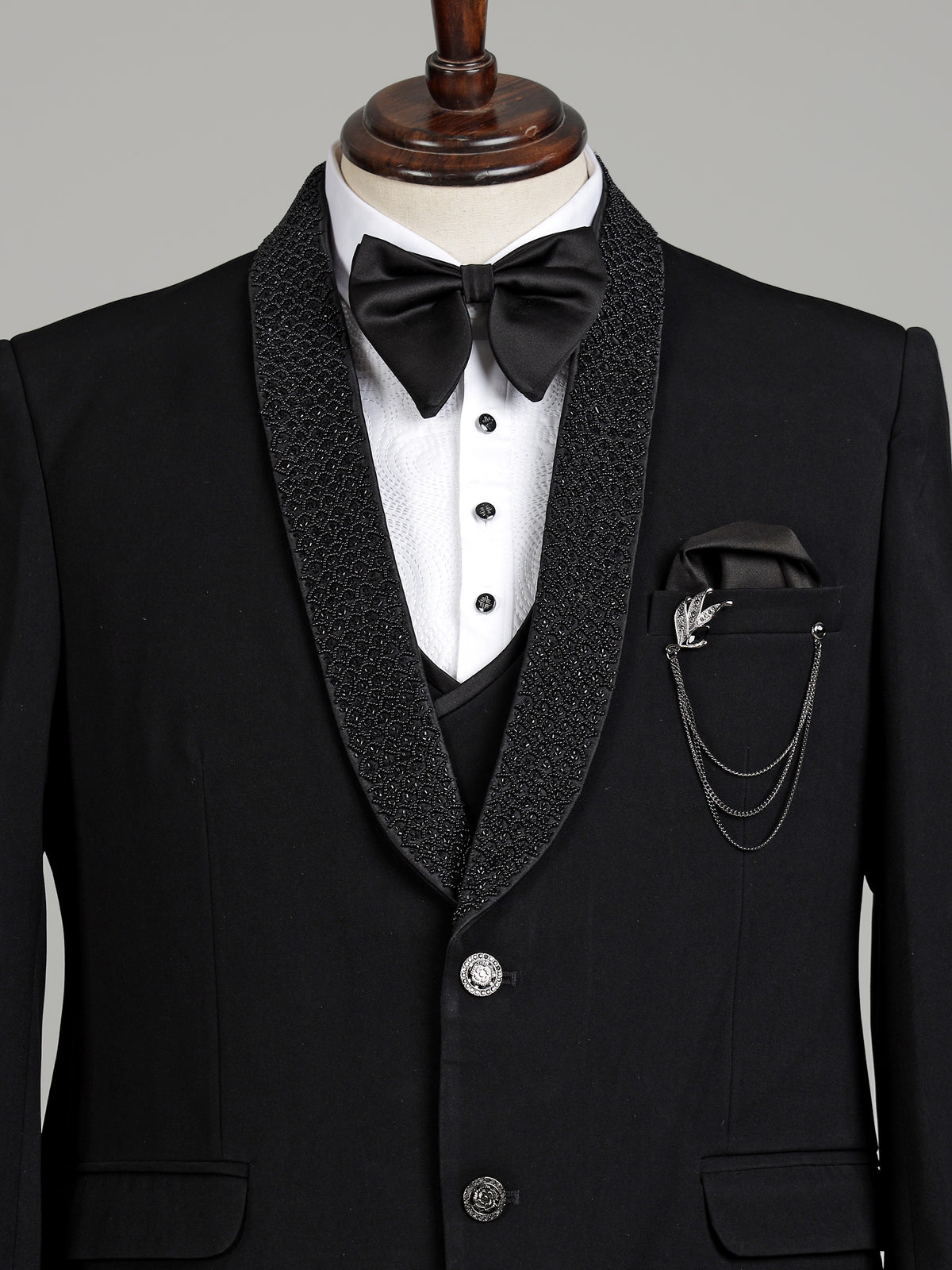 Jet black three-piece tuxedo suit with crystal brooch and cutdana