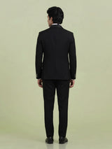 Jet black three-piece tuxedo suit with crystal brooch and cutdana